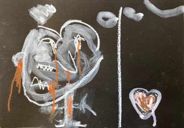 Dibujo a tiza de un rostro con reflejos naranjas y un pequeño corazón sobre una tabla oscura, dividida por una línea vertical.