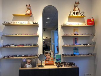 Présentoir de lunettes dans un magasin de lunettes pour enfants avec des étagères, des miroirs et des jouets décoratifs.
