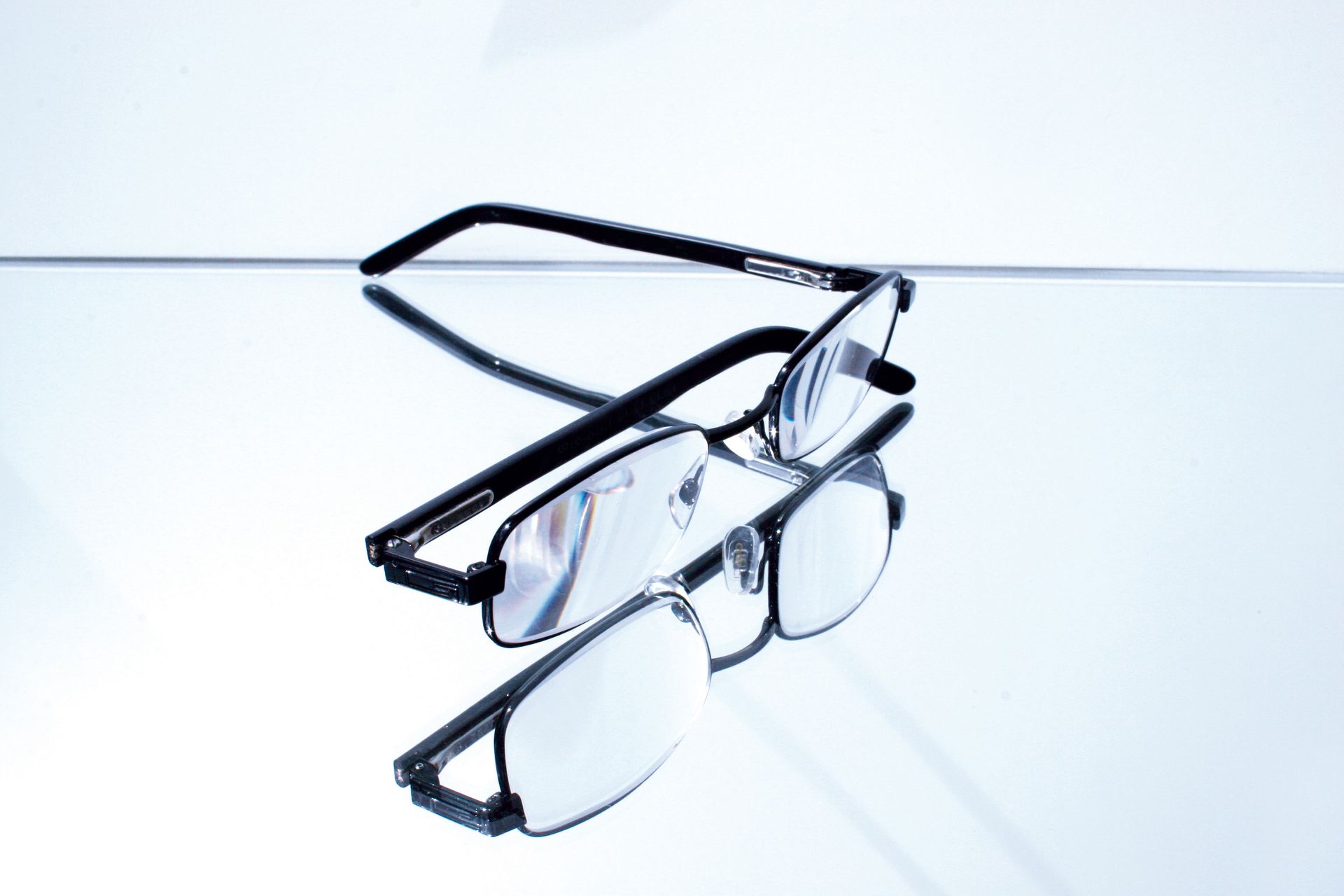 Lunettes noires sur une surface réfléchissante, montrant un reflet miroir des lunettes.