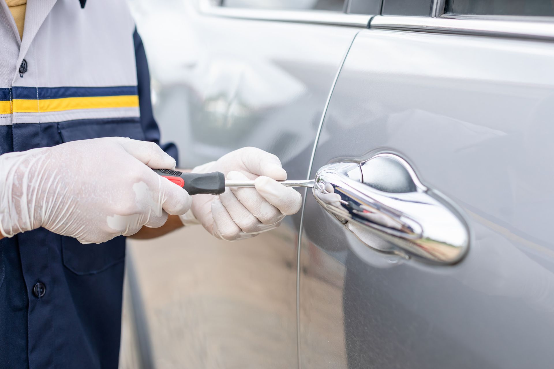 Un hombre est谩 arreglando la puerta de un coche con un destornillador.