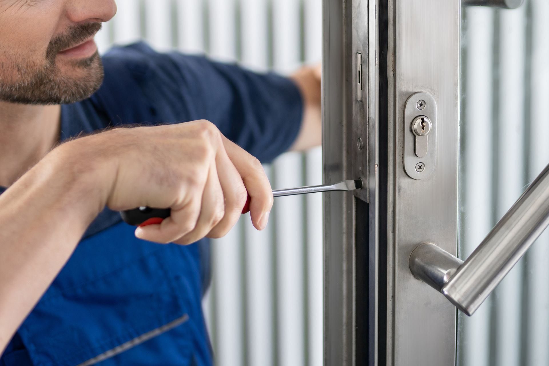 Un hombre est谩 arreglando una puerta con un destornillador.