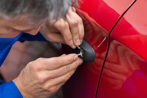 Un hombre está cerrando la puerta de un coche con una llave.