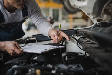 Detailaufnahme eines Kfz-Mechanikers bei der Arbeit im Motorraum.
