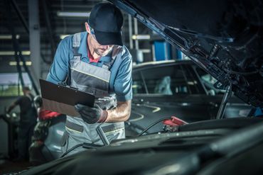 Detailaufnahme eines Kfz-Mechanikers bei der Arbeit im Motorraum.