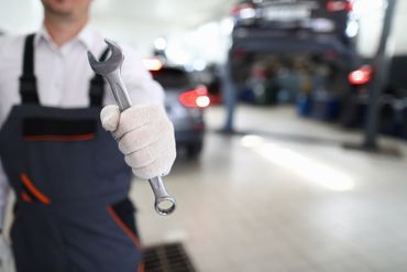 Detailaufnahme eines Kfz-Mechanikers bei der Arbeit im Motorraum.