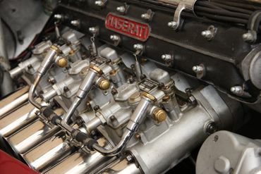 Detailaufnahme eines Kfz-Mechanikers bei der Arbeit im Motorraum.