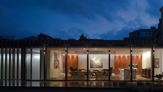 Una casa con muchas ventanas está iluminada por la noche.