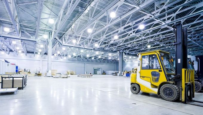 Una carretilla elevadora amarilla está estacionada en un gran almacén.