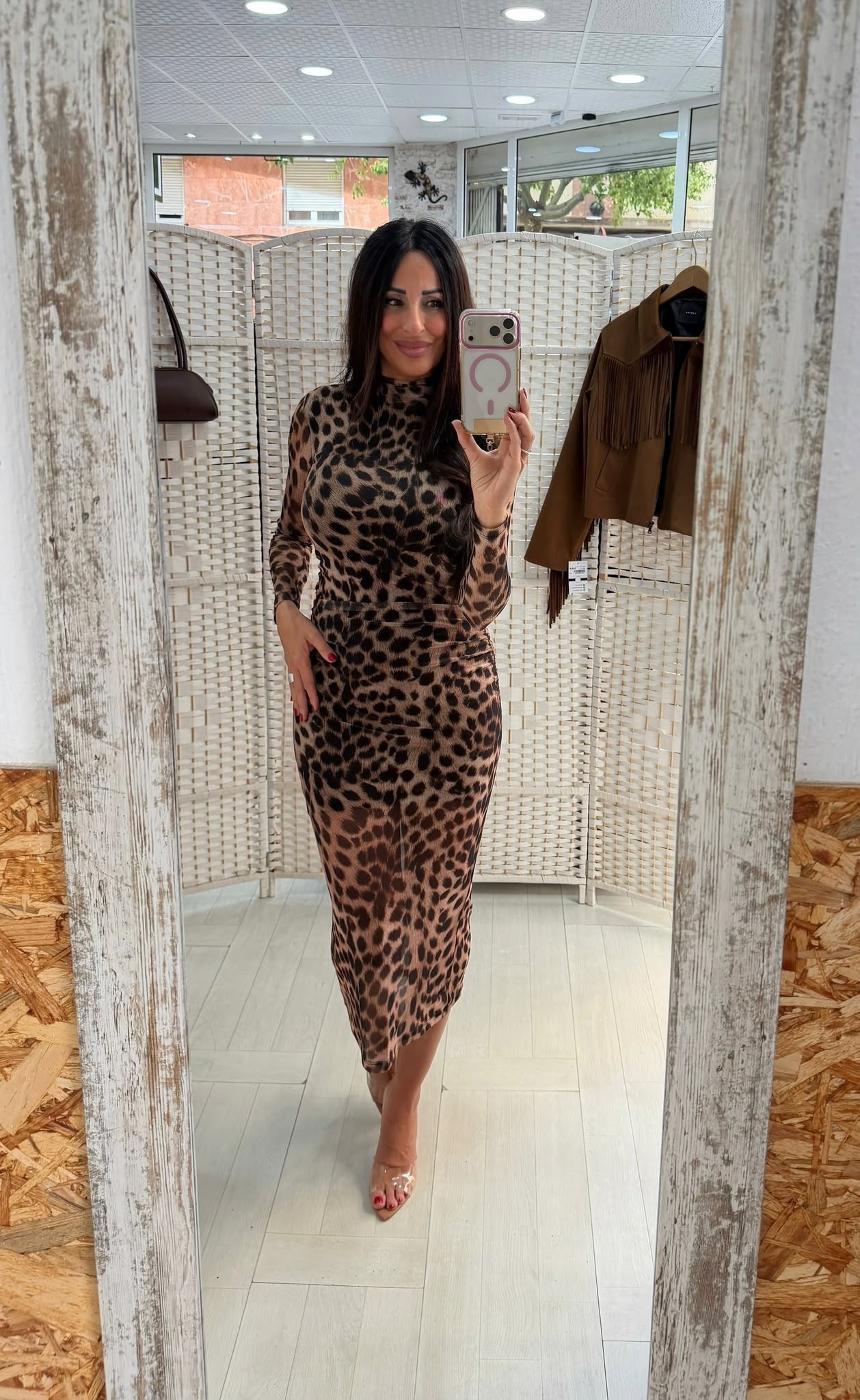 Mujer posando con un vestido de estampado de leopardo en el probador de una tienda de ropa.