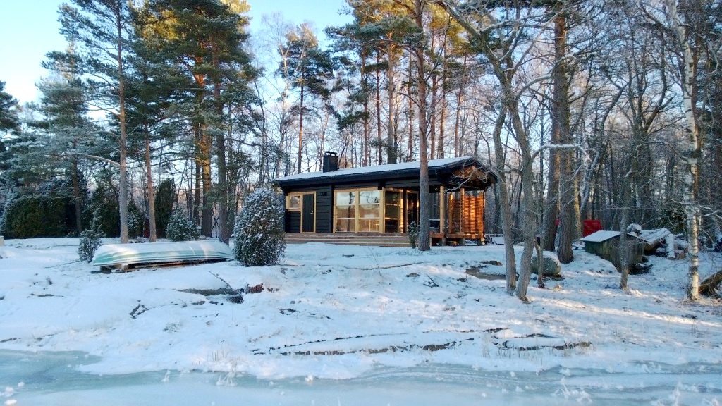 musta lautainen talo talvella metsässä