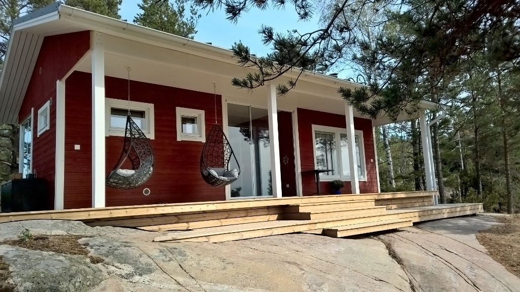 Puna-valkoinen mökki kalliolla metsän syleilyssä