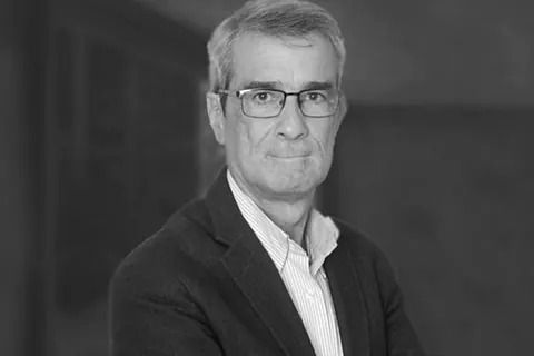 Una fotografía en blanco y negro de un hombre que lleva gafas y traje.