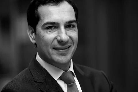 Un hombre con traje y corbata sonríe en una foto en blanco y negro.