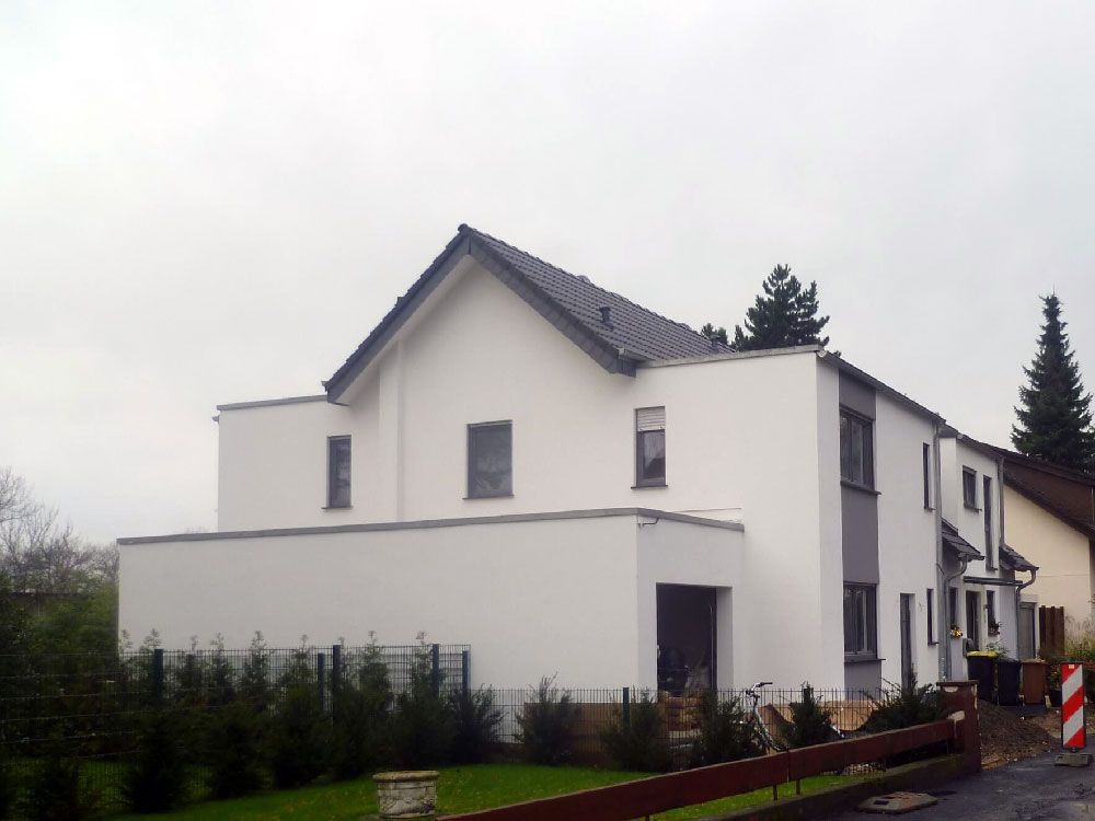 Ein weißes Haus mit einem rot-weißen Zaun davor