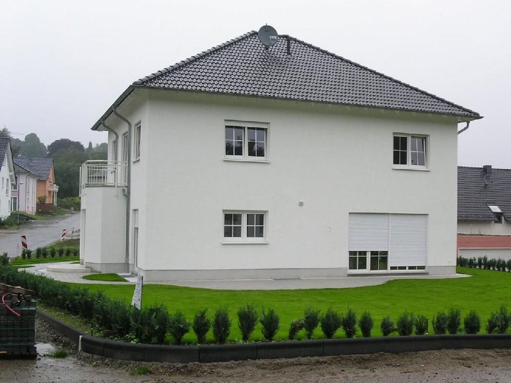 Ein weißes Haus mit einem grauen Dach und vielen Fenstern