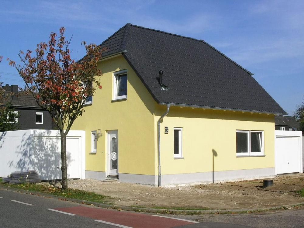 Ein gelbes Haus mit schwarzem Dach und weißen Verzierungen