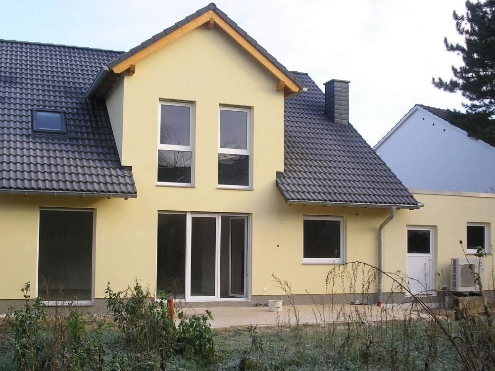 Ein gelbes Haus mit schwarzem Dach und weißen Fenstern