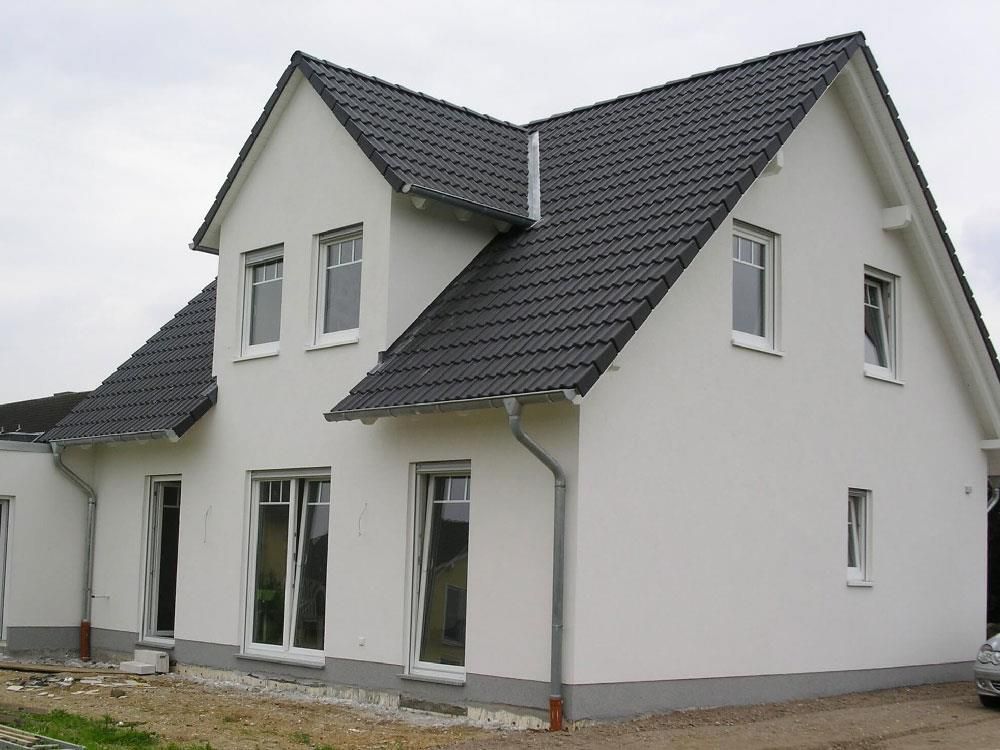 Ein weißes Haus mit schwarzem Dach und weißen Fenstern