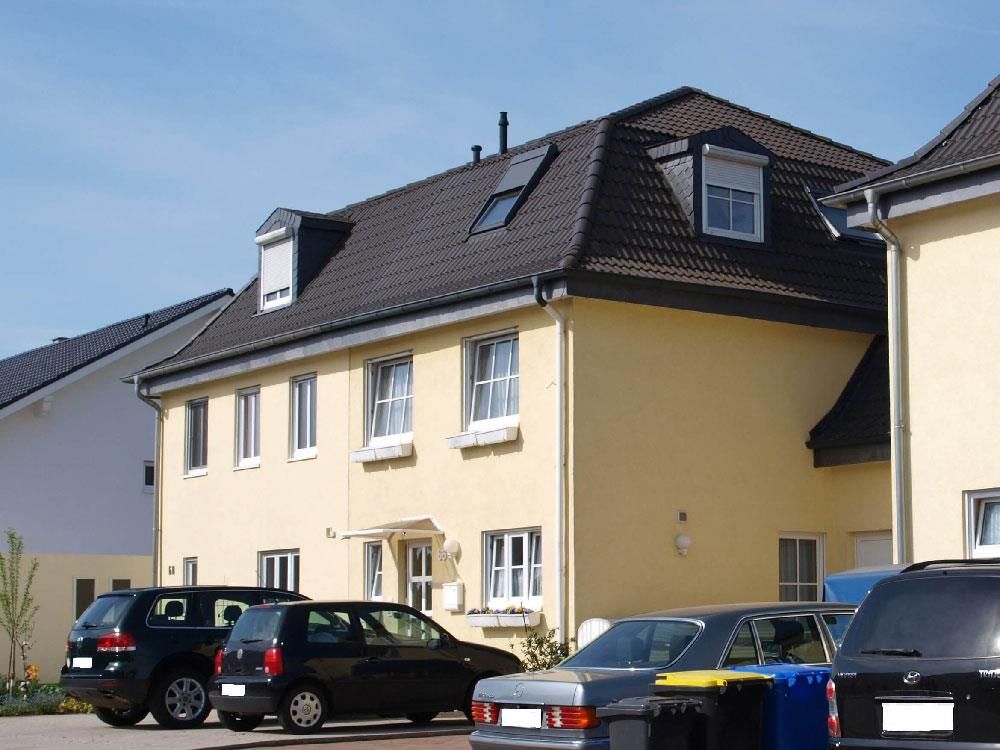 Mehrere Autos parken vor einem gelben Haus