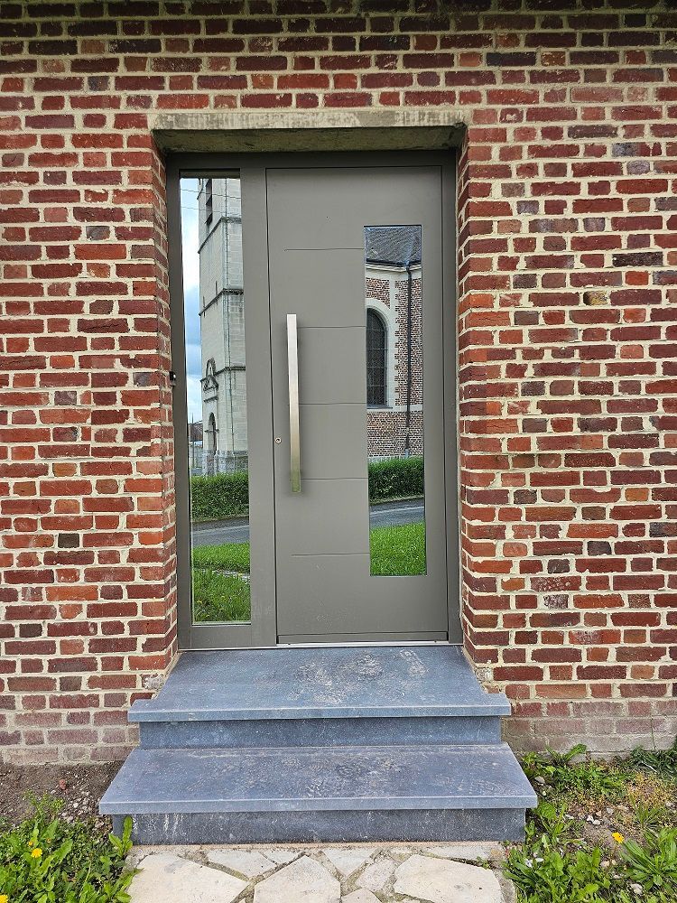 Porte d'entrée en aluminium RAL 7039 gris quartz. Latéral fixe vitrée avec vitrage antélio clair effet miroir. PIERRET.