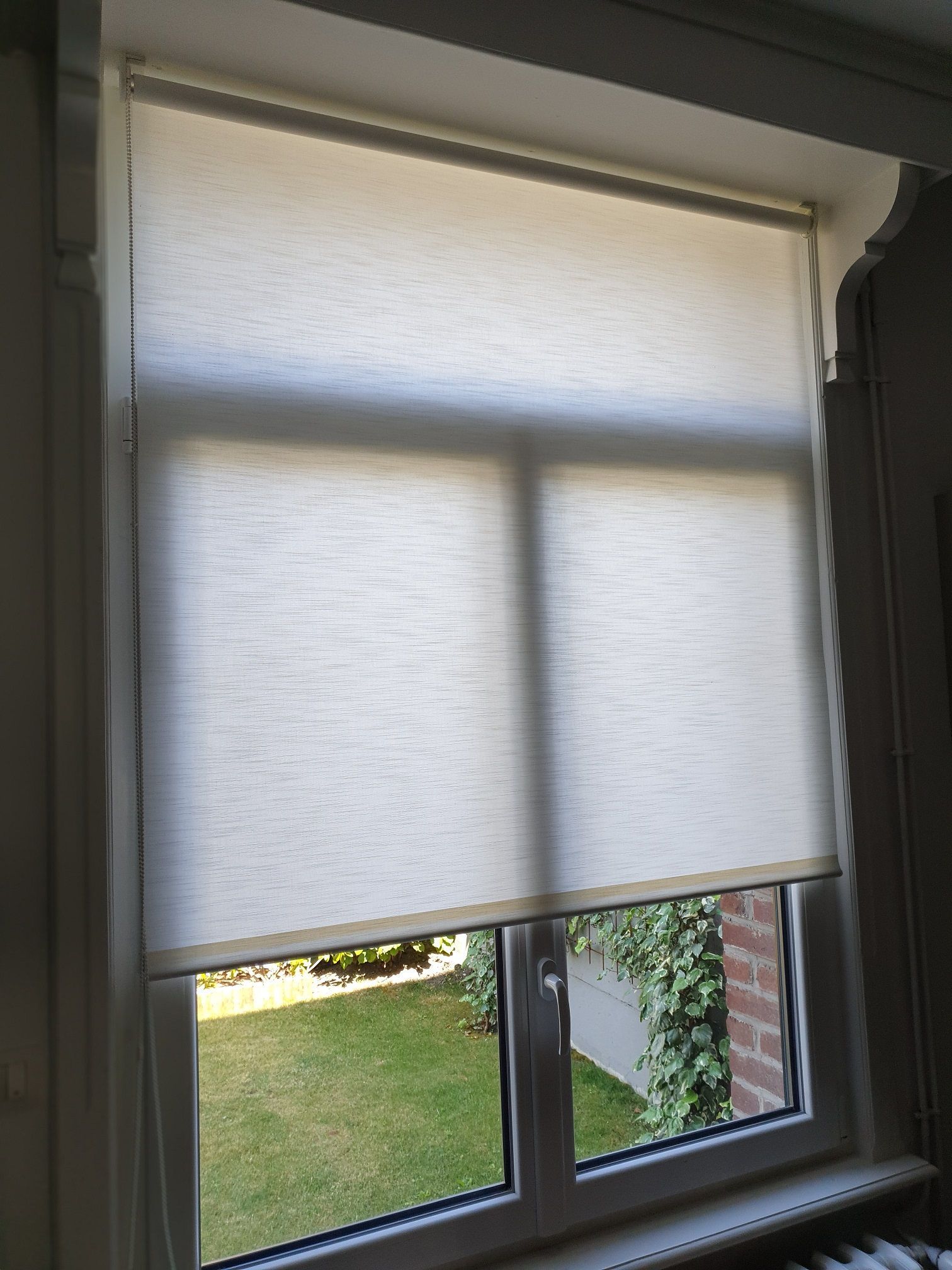 Store d'intérieur. Store rouleau blanc et tissu occultant. Manoeuvre par chaînette/cordon.