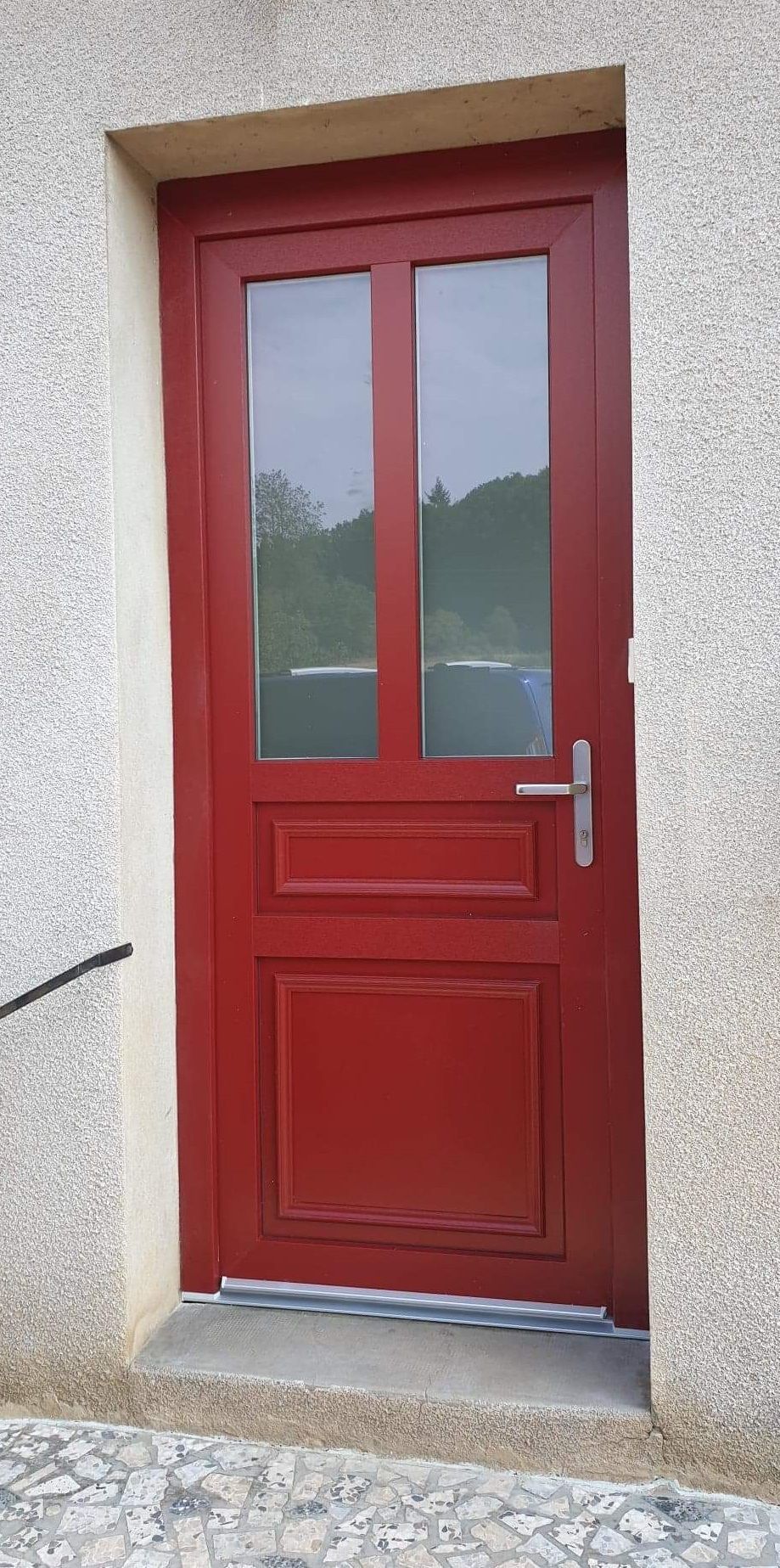Porte d'entrée en PVC filmé rouge extérieur. Modèle demi vitré avec meneau central. Vitrage dépoli acide. SELO.