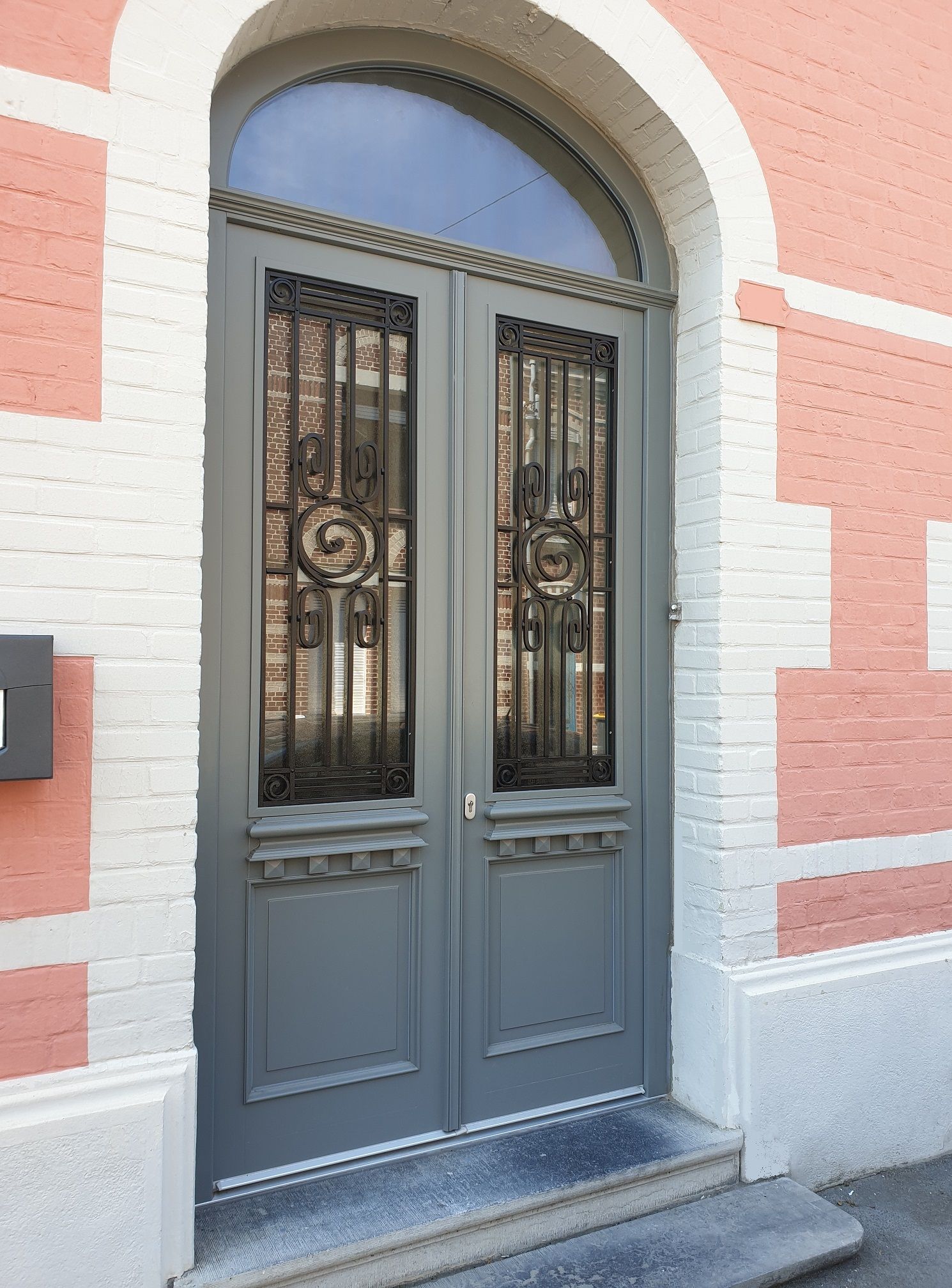 Double porte d'entrée en bois avec grille existante.