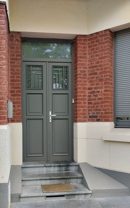 Double porte d'entrée en PVC filmé RAL 7039 gris quartz surmontée d'une imposte fixe vitrée. Vitrage dépoli. PIERRET.