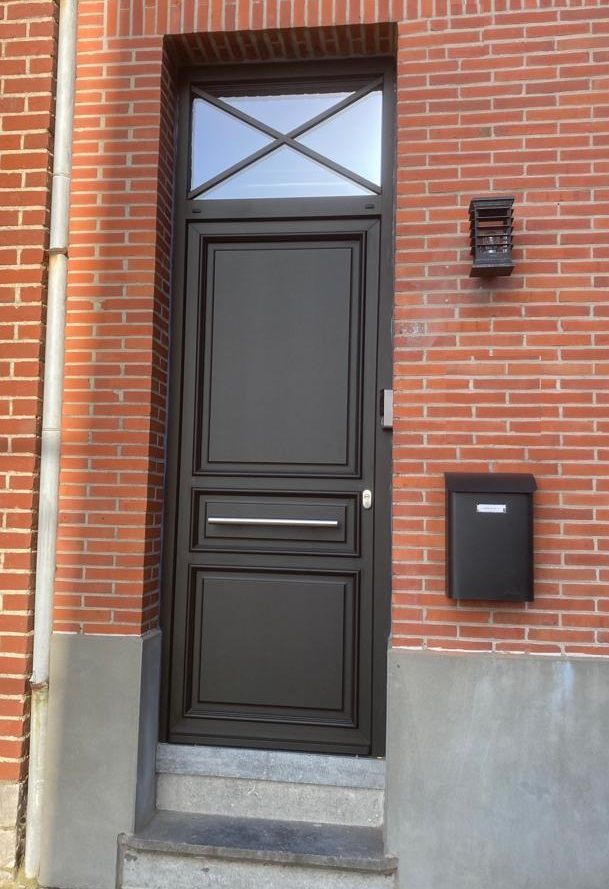 Porte d'entrée à panneau plein en PVC filmé noir RAL 9005 avec imposte fixe vitrée et petits bois appliqués. Fabricant PIERRET.