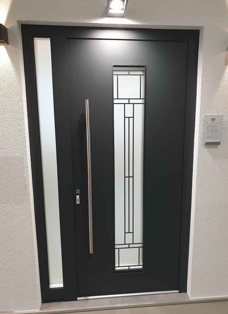 Porte en alu noir avec une partie vitrée au centre. SELO.