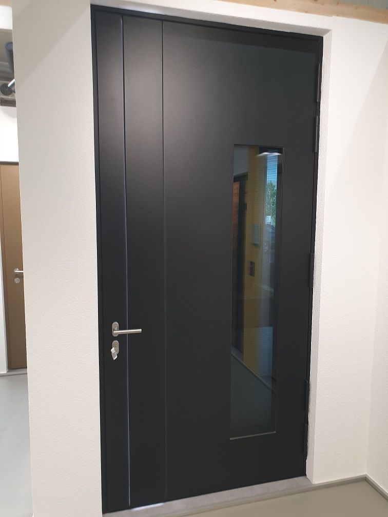 Porte d’entrée aluminium noir avec partie vitrée à gauche.  Fabricant SELO.