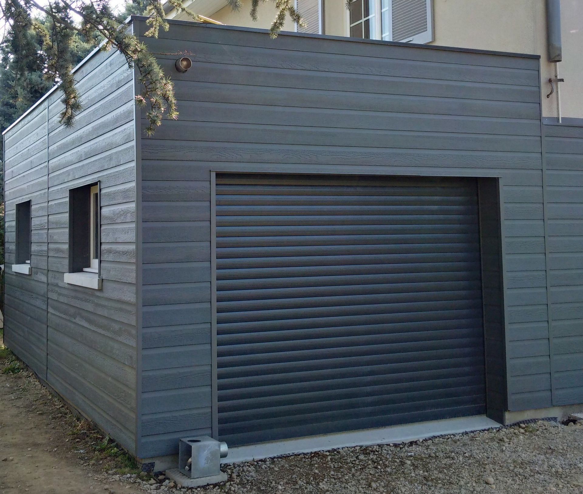 Extension en bardage gris foncé avec porte de garage à enroulement motorisée