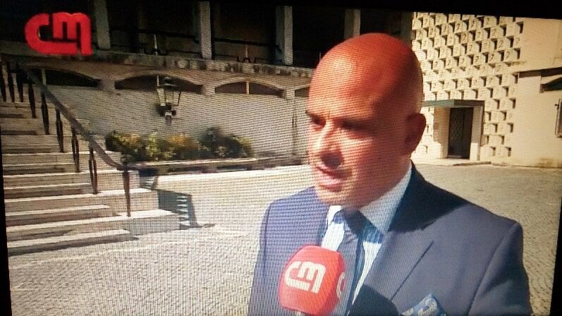 Um homem de terno e gravata está falando em um microfone.