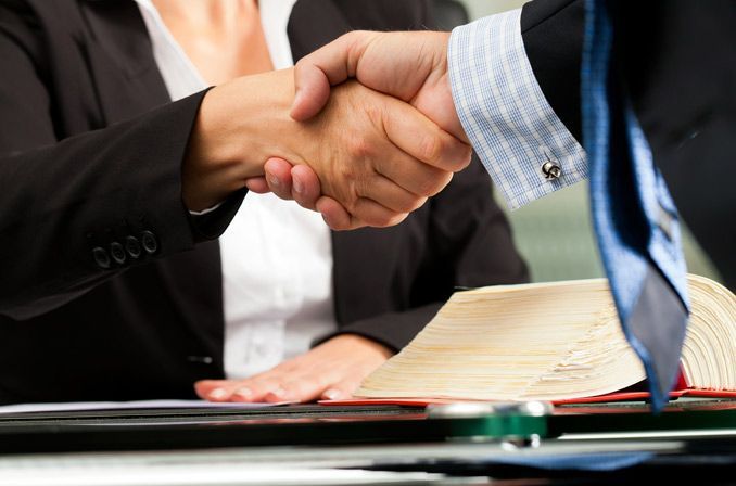 Un hombre y una mujer se dan la mano delante de un libro.