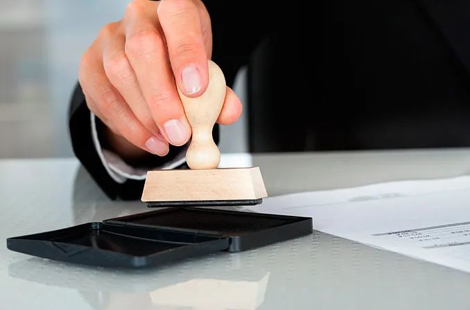 Una persona está sellando un documento con un sello de madera.
