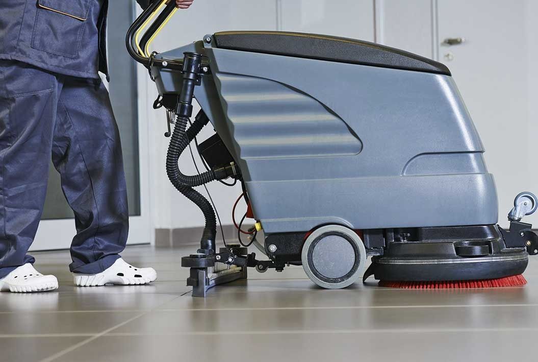 Un hombre está limpiando un piso de baldosas con una máquina.