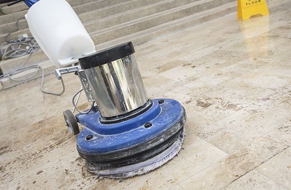 Una máquina está limpiando un piso de baldosas al lado de unas escaleras.