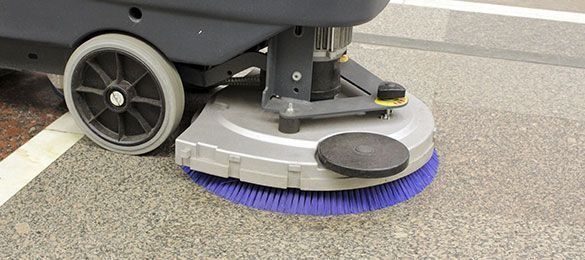Una máquina está limpiando un estacionamiento con un cepillo azul.