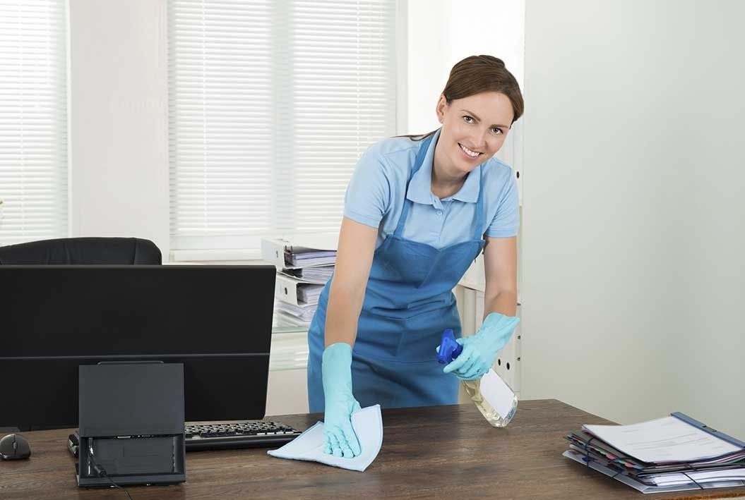 Una mujer está limpiando un escritorio en una oficina.
