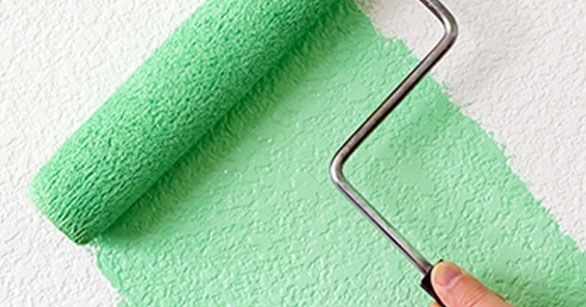 Una persona está pintando una pared con un rodillo de pintura verde.
