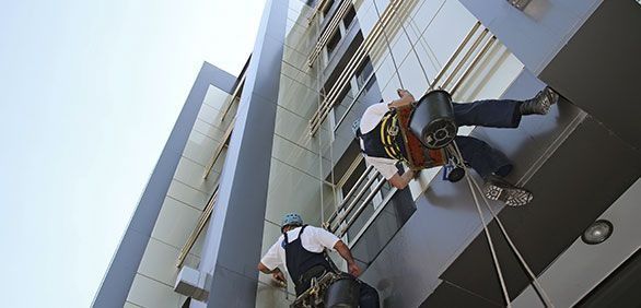 Dos hombres están subiendo por el costado de un edificio alto.