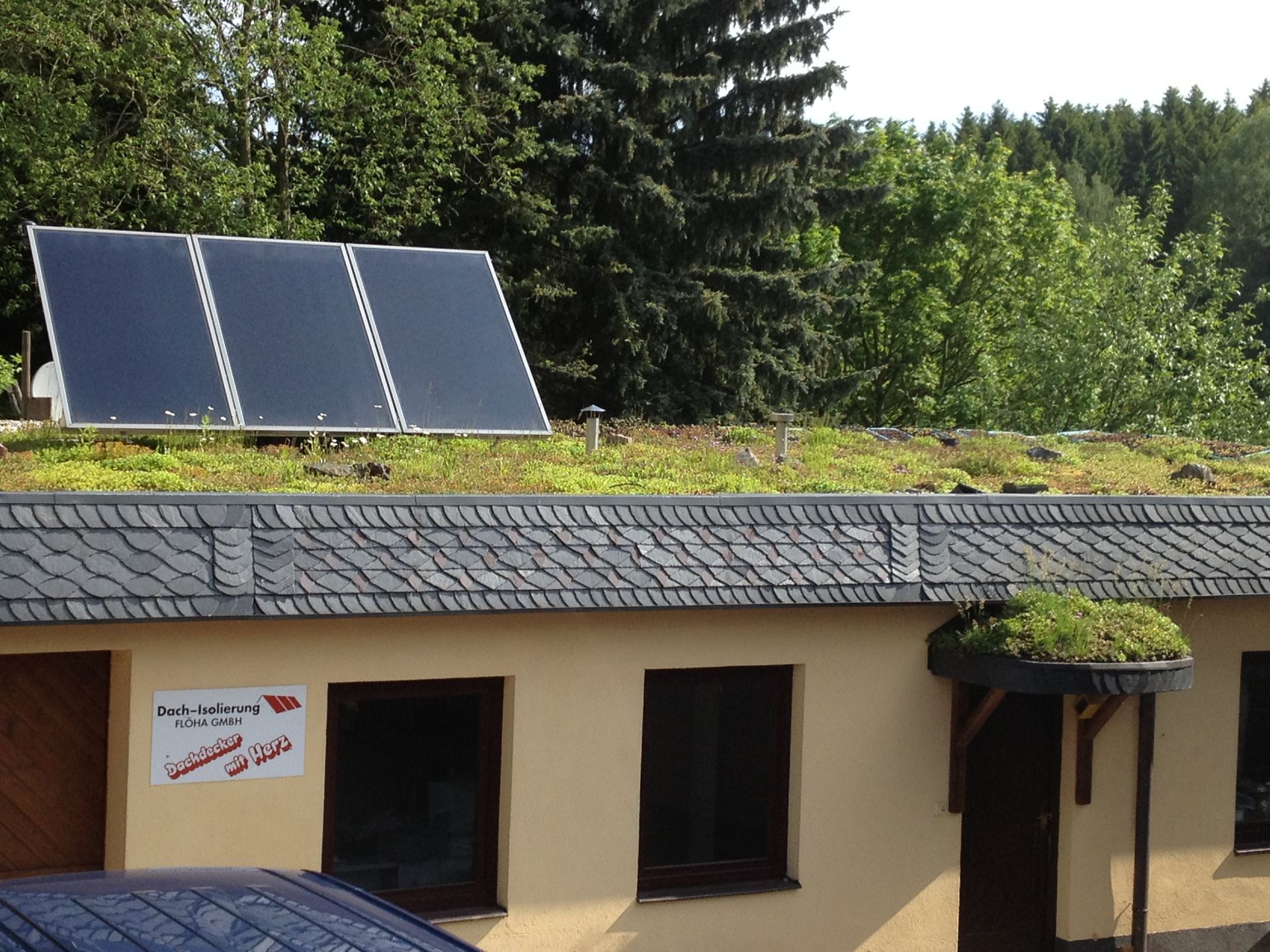 Solarmodule auf einem roten Ziegeldach unter strahlender Sonne und teilweise bewölktem blauem Himmel.