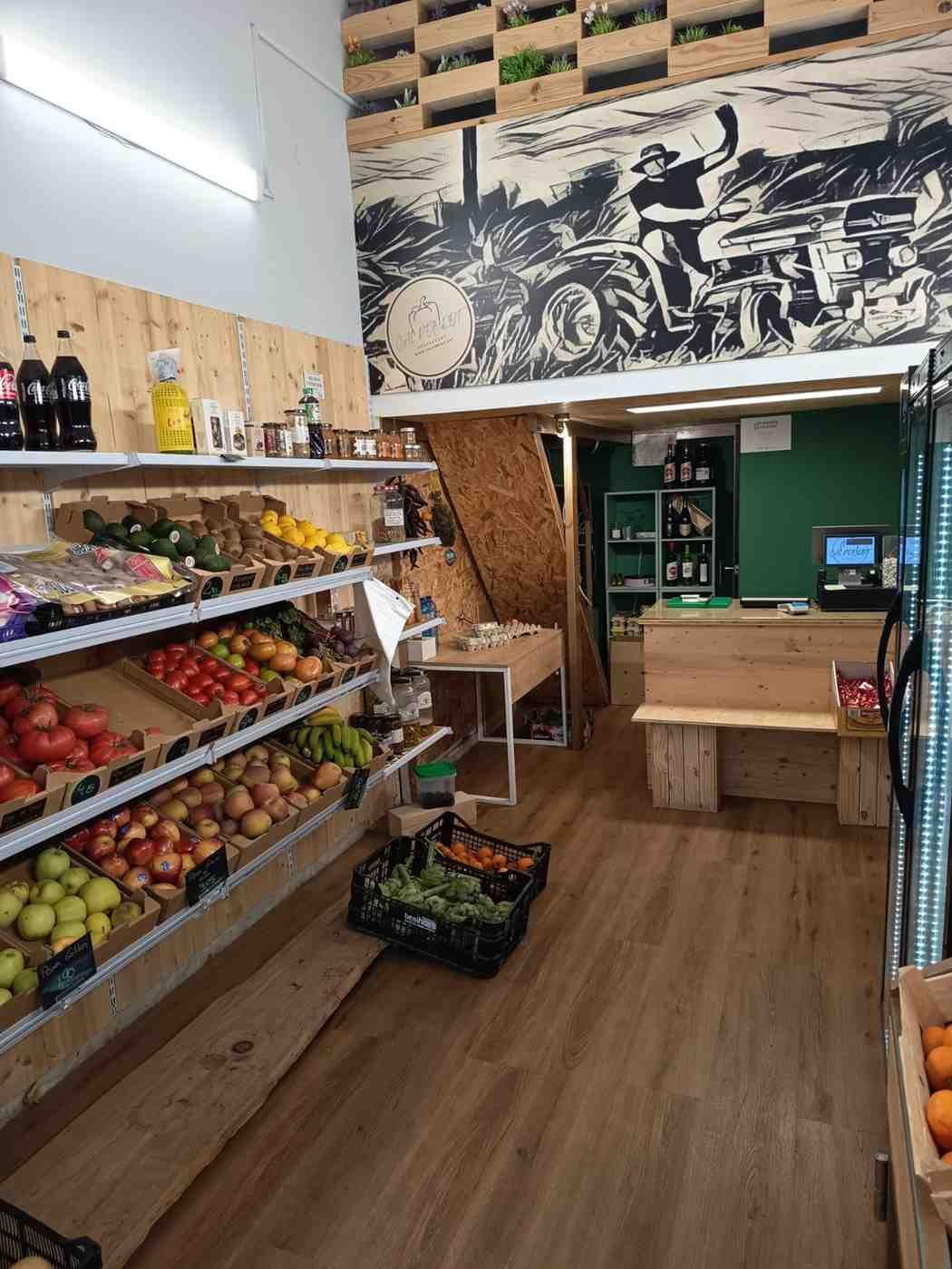 Interior d'una botiga de productes frescos amb prestatges de fusta que mostren fruites i verdures