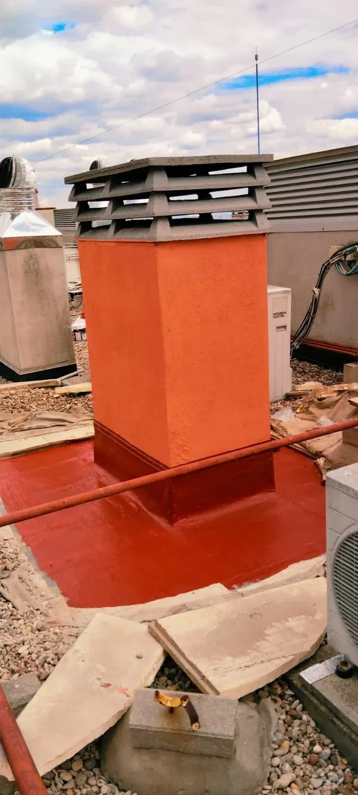 Una gran chimenea naranja está encima de un tejado.