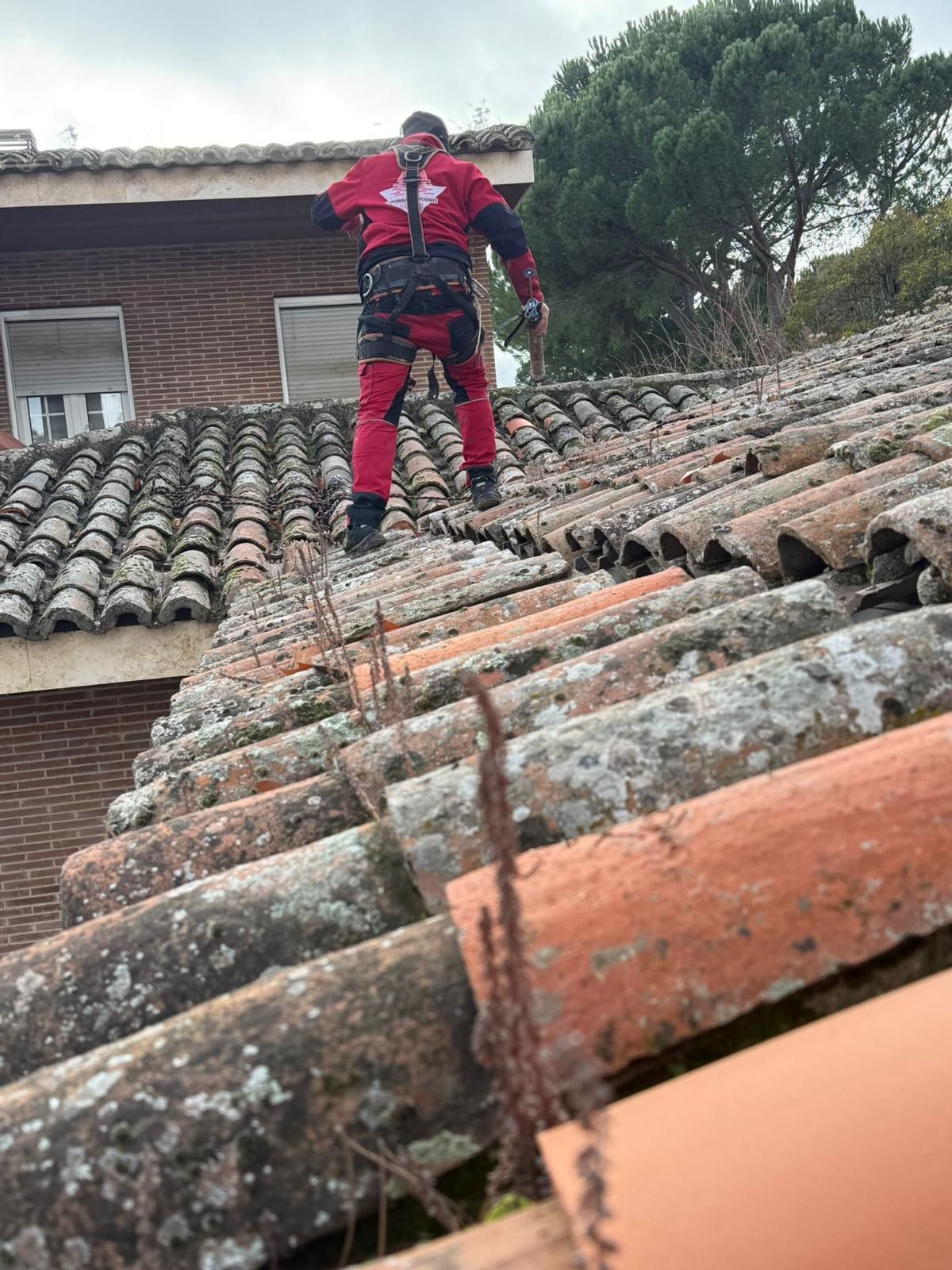 Un hombre está de pie encima de un tejado de tejas.