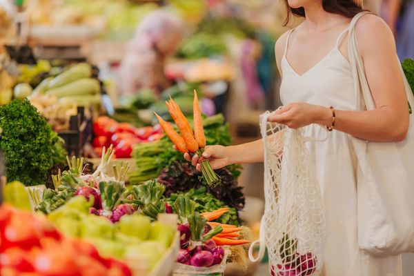 Une femme achète des carottes sur un marché de producteurs.