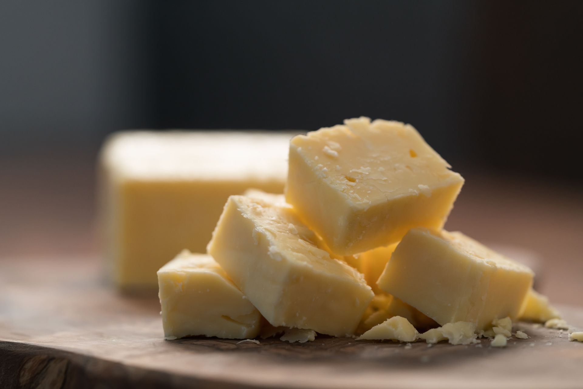 Un tas de morceaux de fromage sur une planche à découper en bois.