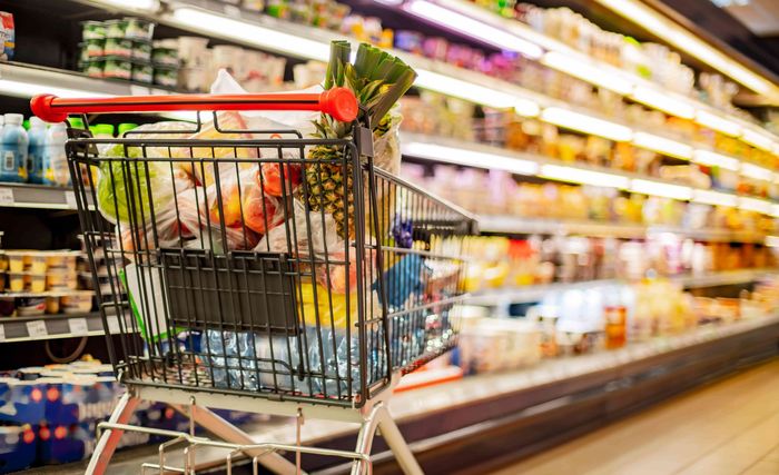 Un caddie rempli de fruits et de légumes dans un supermarché.