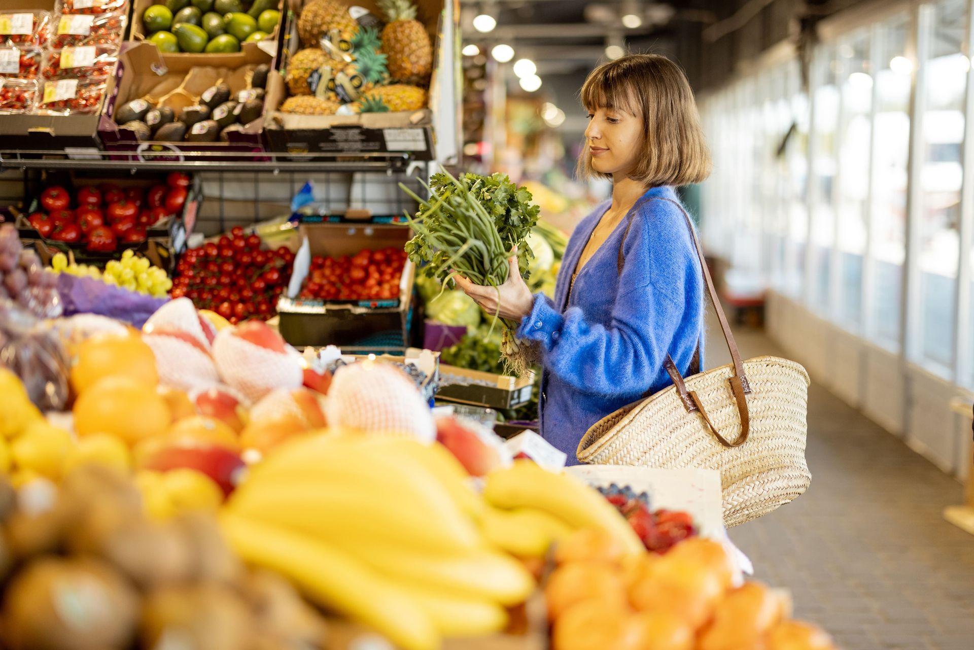 Une femme achète des fruits et des légumes sur un marché.