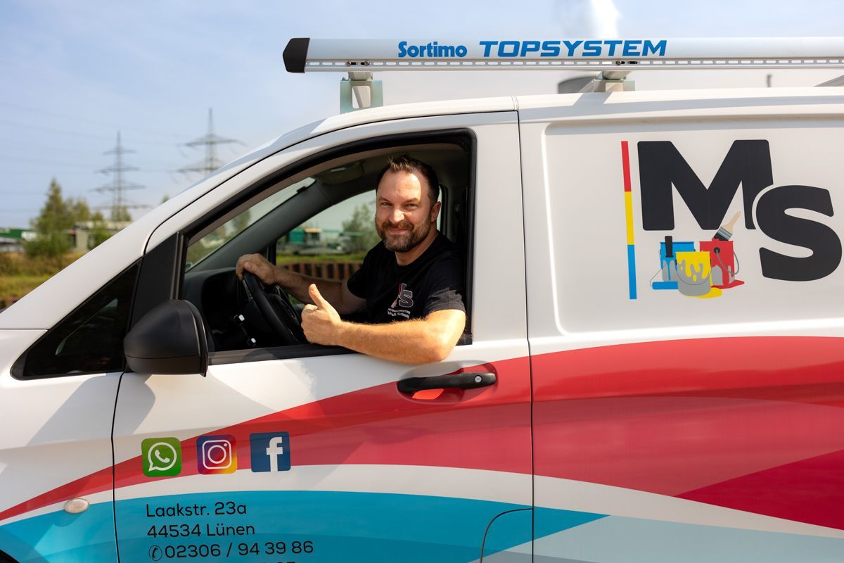 Ein Mann sitzt auf dem Fahrersitz eines MS-Vans und streckt den Daumen nach oben.